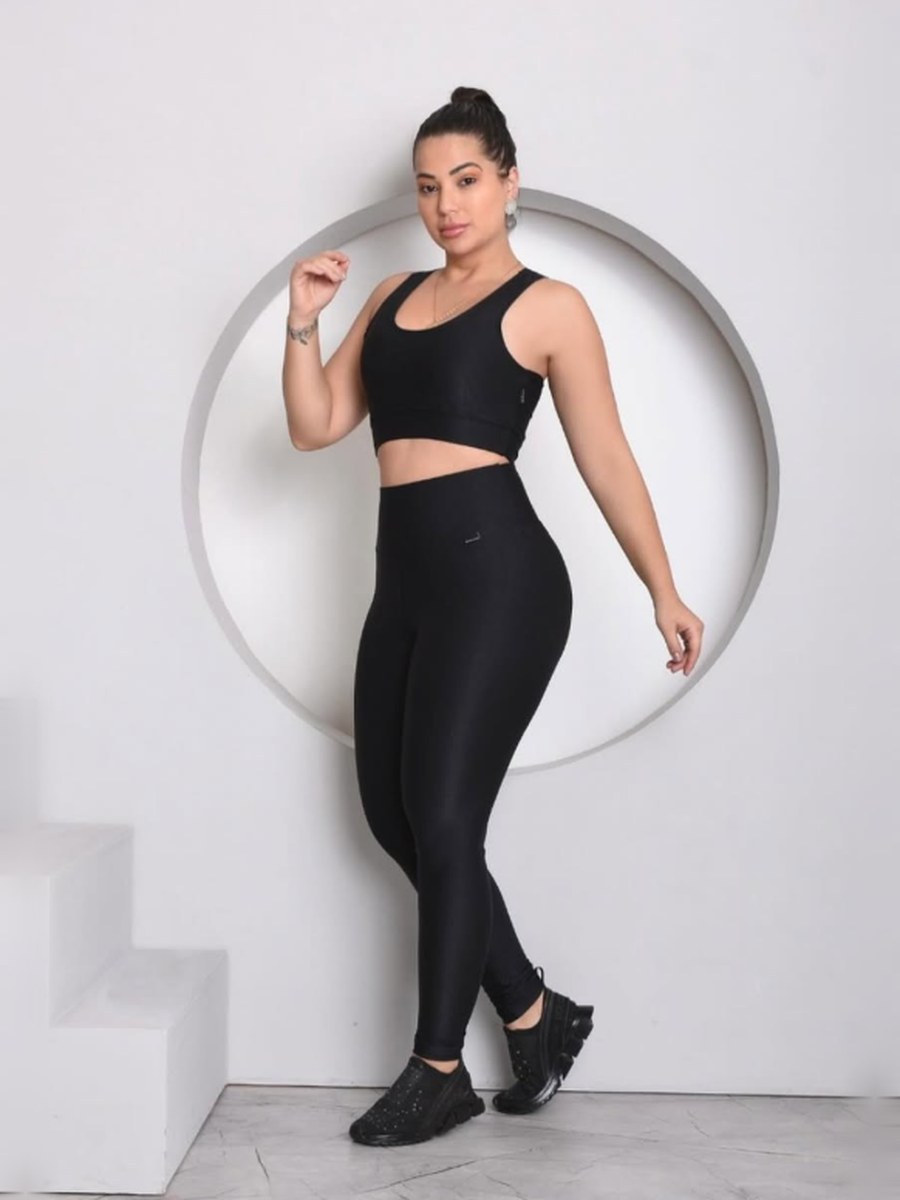 Modelo com conjunto preto diante de um nicho circular branco