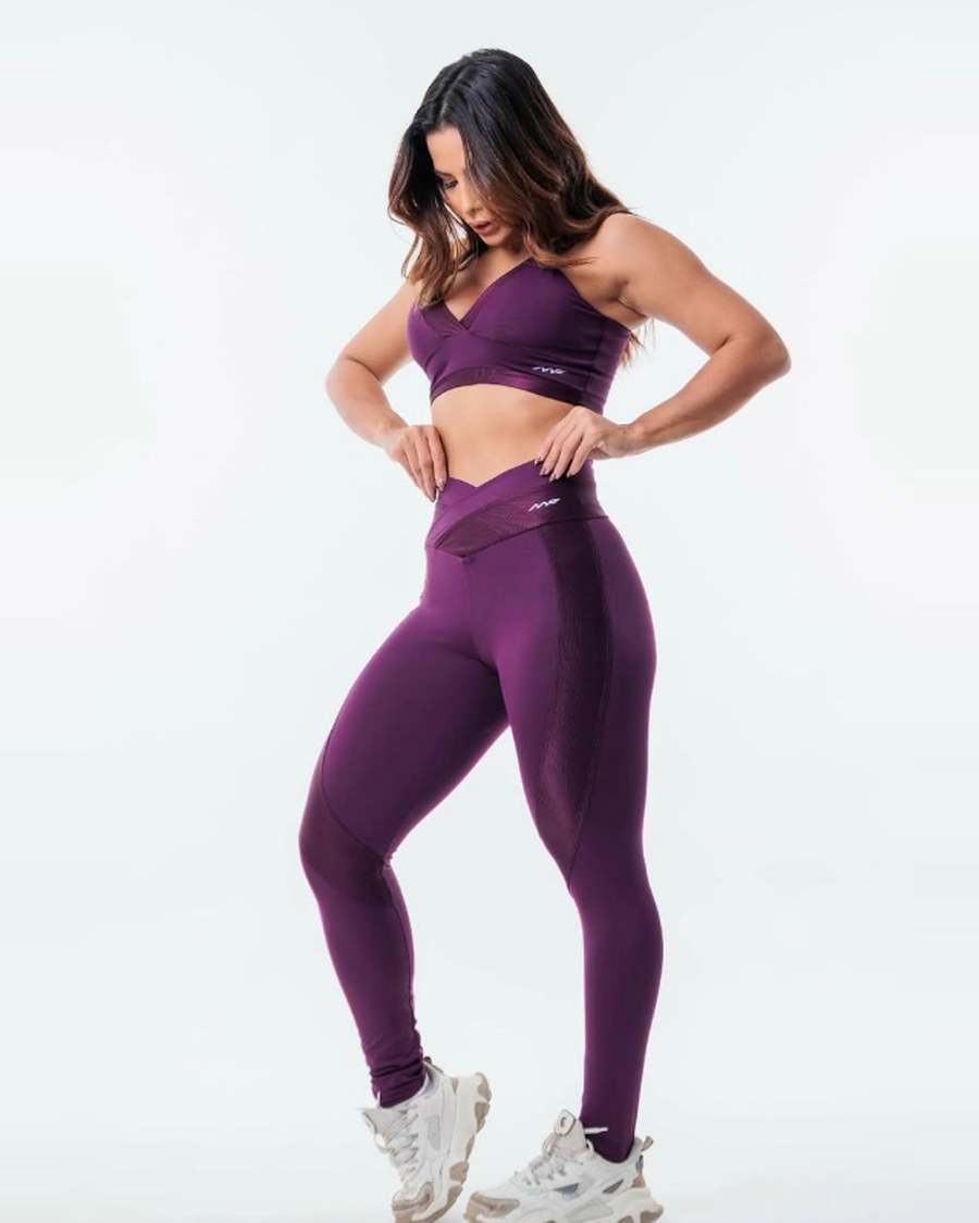 Modelo com conjunto de top e legging na cor ameixa, de frente