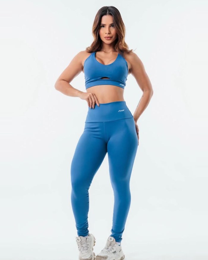 Modelo com conjunto de top e legging na cor azul jeans, de frente